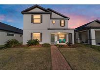 Charming two-story home with a landscaped front yard and welcoming brick pathway at 10597 Grand Oaks Blvd, Oxford, FL 34484