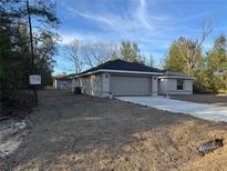 Charming single-story home featuring a two-car garage, neutral paint, and a long driveway at 25 Olive Circle Loop, Ocala, FL 34472