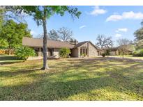 Spacious home with a large yard and mature trees, featuring a stone facade and ample outdoor space at 4425 Se 2Nd Pl, Ocala, FL 34471