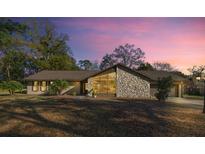 Charming home featuring a unique stone facade and large windows under a beautiful evening sky at 4425 Se 2Nd Pl, Ocala, FL 34471