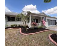 Charming single-story home featuring a well-manicured front yard, white brick exterior, and a welcoming porch with an American flag at 8665 Sw 94Th Ln # C, Ocala, FL 34481