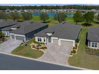 Beautiful single-story home showcasing a large driveway and a tranquil water view in a desirable neighborhood at 8825 Sw 57Th Place Rd, Ocala, FL 34481