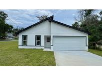 Charming single-story home with a modern design, black trim, white siding, and an attached garage at 31 Juniper Pass Ln, Ocala, FL 34480