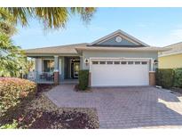 Charming single Gathering home featuring lush landscaping, brick driveway, and two-car garage at 8342 Sw 82Nd Loop, Ocala, FL 34481