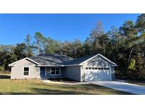 Charming single-story home featuring a gray exterior, a well-manicured lawn, and an attached two-car garage at 114 Bay Dr, Ocklawaha, FL 32179
