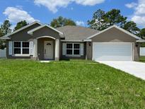 Charming single-story home featuring stucco siding, a well-manicured lawn, and an attached two-car garage at 22081 Sw Pine Bluffs Rd, Dunnellon, FL 34431