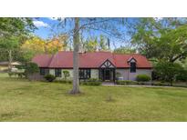 Charming home with a red tiled roof, stone accents, and a lush green lawn, creating a picturesque curb appeal at 411 Sw 38Th St, Ocala, FL 34471