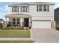 Charming two-story home featuring a manicured lawn, stone accents, and a welcoming front porch at 5021 Sw 88Th St, Ocala, FL 34476