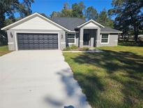 Beautiful single-story home with a well-manicured lawn, concrete driveway, and attached two-car garage at 7677 Sw 81St Pl, Ocala, FL 34476