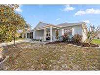 Charming single-story home boasts a screened porch, manicured lawn and vibrant red flower bushes at 9770 Sw 97Th Pl, Ocala, FL 34481