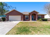 Charming single-story home with a stucco exterior, arched entry, and well-maintained lawn on a sunny day at 16272 Se 89Th Ct, Summerfield, FL 34491