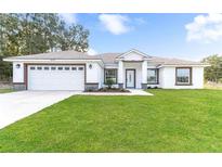 Charming single-story home with a well-manicured lawn and attached two-car garage at 8330 Se 161St St, Summerfield, FL 34491