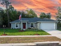 Charming single-story home with manicured lawn, red door, and two-car garage at 15428 Sw 60Th Cir, Ocala, FL 34473