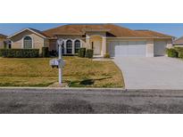 Charming single-story home showcasing a well-maintained lawn and a two-car garage in a sunny setting at 5115 Nw 21St Loop, Ocala, FL 34482