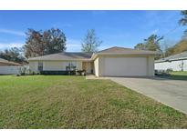 Charming single-story home with a well-maintained lawn and two-car garage on a sunny day at 7 Fir Drive Trce, Ocala, FL 34472