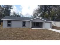 Charming single-story home with gray stucco, a modern roof, an attached garage, and a well-manicured lawn at 734 Nw 57Th Ave, Ocala, FL 34482