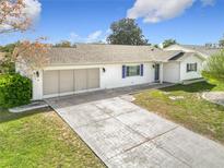Charming single-story home with a well-maintained lawn, brick driveway, and attached two-car garage at 9886 Se 178Th Ln, Summerfield, FL 34491