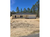 New construction home featuring neutral colors, an attached garage, and front yard surrounded by tall trees at 1370 Sw Obee Ridge Rd, Dunnellon, FL 34432
