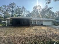 Charming single-story home with a screened-in porch, lush trees, and well-maintained landscaping at 13949 Se 53Rd Ave, Summerfield, FL 34491