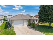 Charming single-story home with a well-manicured lawn, decorative driveway, and a two-car garage on a sunny day at 17959 Se 89Th Natchez Ave, The Villages, FL 32162