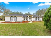 Charming single-story home featuring a white exterior, arched windows, and a well-maintained front yard with a landscaped pathway at 3621 Sw 52Nd Ter, Ocala, FL 34474