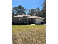 Charming single story home featuring a well-maintained lawn, attached garage, and welcoming entrance at 6884 Sw 149Th Lane Rd, Ocala, FL 34473