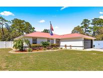 Charming home features a manicured lawn, vibrant landscaping, and a striking red roof at 1192 Ne 130Th Ter, Silver Springs, FL 34488