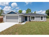 Charming single-story home featuring a gray exterior, a two-car garage, and a well-maintained lawn at 2 Hemlock Ter Dr, Ocala, FL 34472