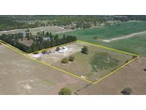 An aerial view of a property with a large open field, treeline, residence, and a yellow boundary line at 2061 Nw 165Th Court Rd, Dunnellon, FL 34432
