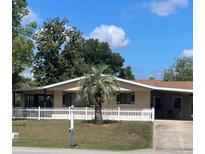 Charming single-story home with a well-manicured lawn, picket fence, and a beautiful palm tree in the front yard at 10040 Sw 98Th Ave, Ocala, FL 34481