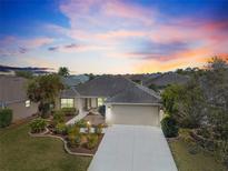 Charming single-story home featuring a two-car garage and nicely landscaped front yard at sunset at 3407 Melbourne Ln, The Villages, FL 32163