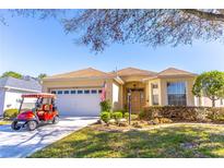 Charming home featuring a well-manicured lawn, two-car garage, and a red golf cart at 9458 Sw 93Rd Loop, Ocala, FL 34481