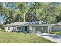 Charming single-story home featuring a well-maintained lawn, gray siding, and a two-car garage at 211 Oak Lane Cir, Ocala, FL 34472