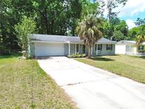 Cozy single-story home with an attached garage, palm tree and a long driveaway providing ample parking space at 736 Ne 26 Ter, Ocala, FL 34470