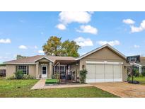 Charming single-story home featuring a two-car garage and a cozy front porch with a pergola at 33827 Silver Pine Dr, Leesburg, FL 34788