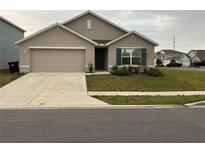 Charming single-story home featuring a beige exterior, a two-car garage, and a neatly maintained front lawn at 4931 Sw 88Th Pl, Ocala, FL 34476