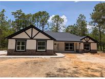 Charming single-story home featuring black trim, stone accents, and a well-maintained lawn surrounded by mature trees at 6150 Sw 123 Ave Rd, Dunnellon, FL 34432