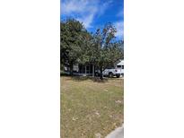 Exterior view showing the lawn, vehicle, and front screened-in porch of the residence at 10934 Luana Dr, Leesburg, FL 34788