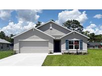 Charming single-story home featuring a two-car garage, manicured lawn, and elegant blue shutters at 16805 Sw 50Th Cir, Ocala, FL 34473