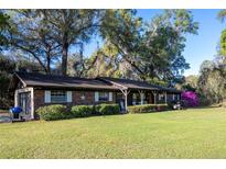 Charming brick home with a well-maintained lawn and mature trees offering shade and curb appeal at 2570 Se Highway 42, Summerfield, FL 34491