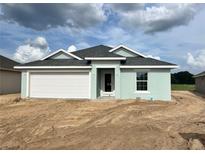 Charming single-story home with a two-car garage, light blue paint, and a well-maintained yard under a cloudy sky at 4504 Sw 90Th Lane Rd, Ocala, FL 34476