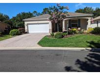 Well-maintained single-story home featuring a paved driveway, manicured lawn, and inviting front porch with seating at 8344 Sw 79Th Cir, Ocala, FL 34476
