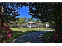 Charming two-story home with columns and a well-manicured lawn, framed by trees and vibrant pink flowers at 2881 Se 41St Pl, Ocala, FL 34480