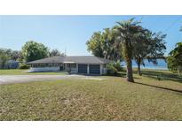 Expansive single story home featuring a two car garage and a large yard with mature trees on a sunny day at 390 Sw Shorewood Dr, Dunnellon, FL 34431