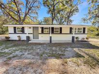 Charming single-story home with a minimalist design, gray door and black window shutters at 5311 Nw 27Th Ave, Ocala, FL 34475