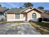 Charming single-story home featuring a concrete driveway, tidy yard, and light pink painted exterior at 3617 Westland Dr, Orlando, FL 32818