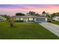 Charming single-story home with a well-manicured lawn and a screened-in garage at dusk at 10190 Se 178Th St, Summerfield, FL 34491