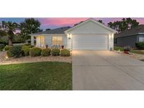 Charming home featuring a two-car garage, beautiful landscaping, and a cozy front patio at 11828 Se 91St Cir, Summerfield, FL 34491
