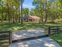 Lovely ranch-style home featuring an iron gate, mature trees, and a well-maintained lawn at 16 Northern Dancer Dr, Ocala, FL 34482