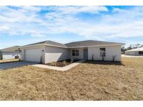 Charming single-story home featuring a clean stucco facade, attached garage, and a neatly maintained front yard at 1698 Ne 161 St, Citra, FL 32113